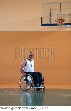 a war  in a wheelchair trains with a ball at a basketball club in training with professional sports equipment for the disabled. the concept of sport for people with disabilities