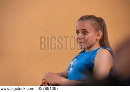 a portrait of a woman with a disability sitting in a wheelchair waiting for a basketball game to begin