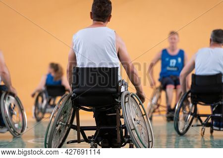 Close up photo of wheelchairs and handicapped war veterans playing basketball on the court