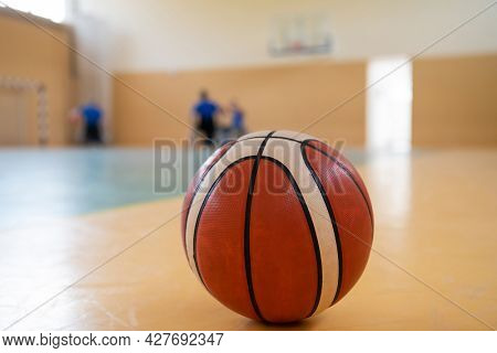 close up photo of a basketball on the court, in the background a sports team of people with disabilities preparing for a game