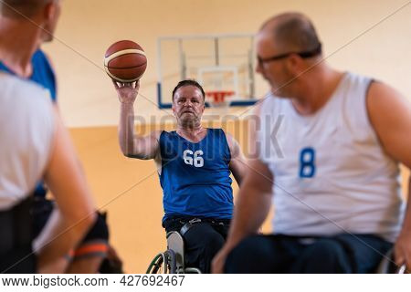 handicapped war veterans in wheelchairs with professional equipment play basketball match in the hall.the concept of sports with disabilities