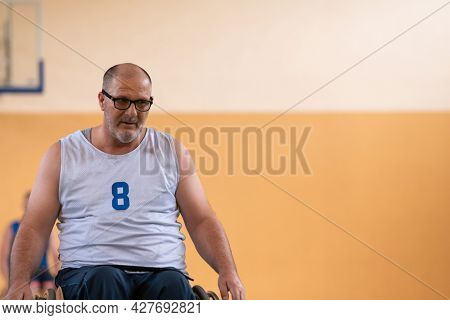 a photo of a war veteran playing basketball with a team in a modern sports arena. The concept of sport for people with disabilities