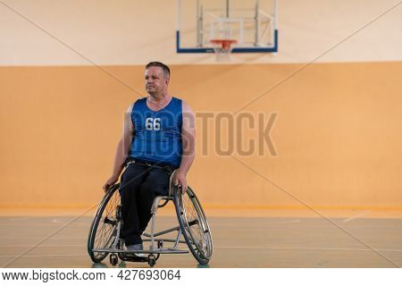 a photo of a war veteran playing basketball with a team in a modern sports arena. The concept of sport for people with disabilities