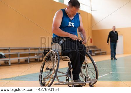a photo of a war veteran playing basketball with a team in a modern sports arena. The concept of sport for people with disabilities