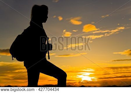 Woman Walking On Top Of Mountain At Twilight With Sun Ray Under Her Feet