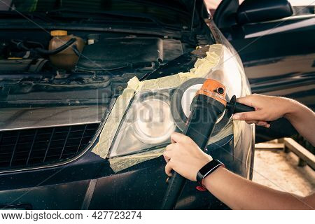 Cleaning Headlights With A Buffer Machine. The Master Polishes The Headlights Of The Car.