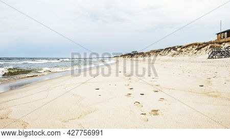 Sea Waves And Footprints On The Sand On The Beach And Overcast Sky