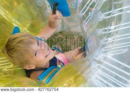 A Child In A Bumperball. Portrait Of A Happy Laughing Child. Happiness, Fun And Laughter