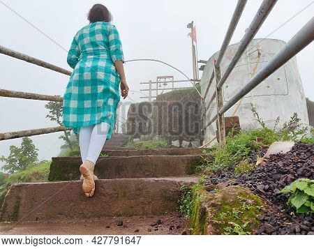 Back View Of A 20-25 Years Old Indian Girl Wearing Blue Color Top And White Leggings Climbing Wet St
