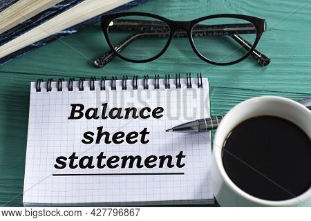 Balance Sheet Statement - Words In A Notepad On A Wooden Green Background With A Calculator, Pen And