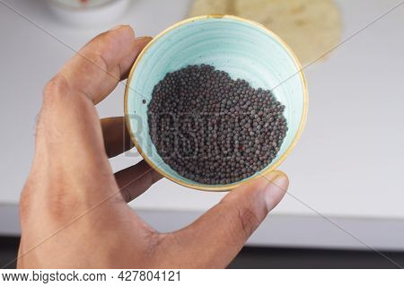 Mustard Seeds Bowl In Hand Isolated On Light Background.