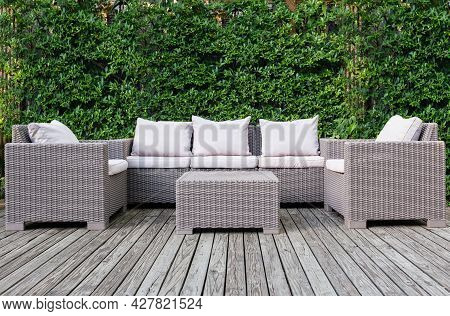 Beautiful Wooden Terrace With Rattan Garden Furniture With Greenery Background.