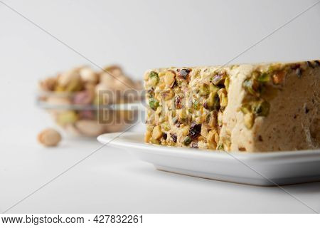 Organic Halva With Pistachios On A White Plate Isolated On White. Traditional Middle Eastern Sweets.