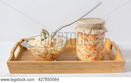 Sauerkraut In A Jar And A Bowl. Sauerkraut With Carrots In A Wooden Tray On A White Background. Ferm