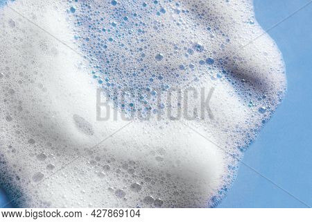 Face Cleansing Mousse Sample. White Cleanser Foam Bubbles On Blue Background. Soap, Shower Gel, Sham