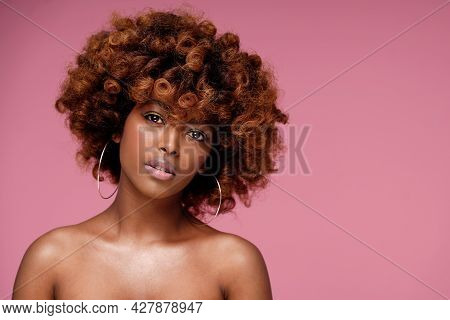 Beauty Portrait Of Afro Woman With Glamour Summer Makeup And Curly Hairstyle. Pink Pastel Background