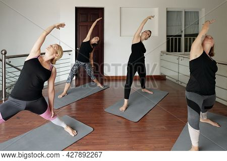Fit Young Women Attanding Yoga Class And Doing Reverse Warrior Pose That Help To Release Tension In 