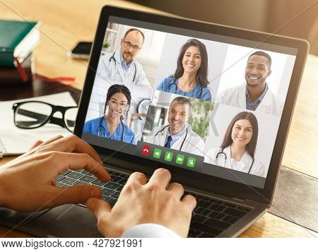 Closeup Of Doctor Using Laptop Video Calling Colleagues At Workplace