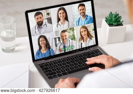 Unrecognizable Female Doctor Using Laptop Computer Communicating With Colleagues Online