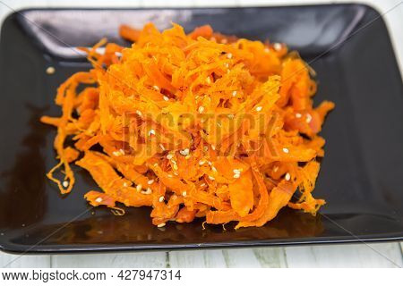 Squid (lat. Teuthida) Shavings In Shanghai On A Black Rectangular Plate With A Wooden Table Backgrou