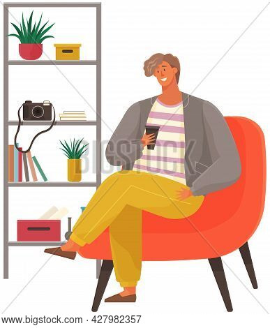 Stylish Man Sitting On Armchair Holding Cup In Hand Drinking Coffee. Male Character Has Rest In Apar