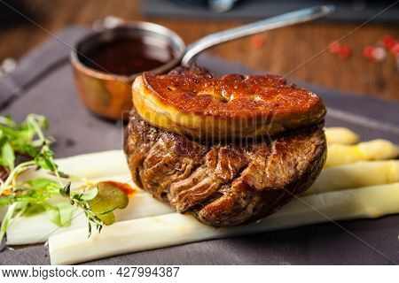 Tournedos Rossini. Foie gras, Black Angus beef tenderloin, white asparagus, red wine sauce. Delicious healthy traditional food closeup served for lunch in modern gourmet cuisine restaurant.