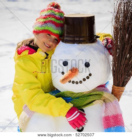 Winter fun, happy kid playing with snowman