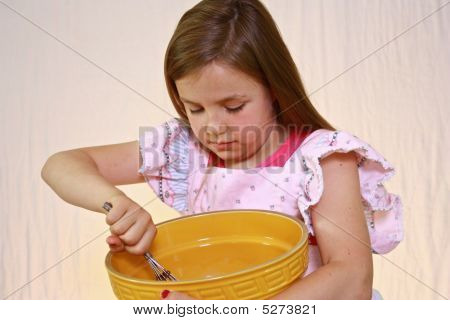 若いとかわいい女の子をピンクのエプロンのボウル。
