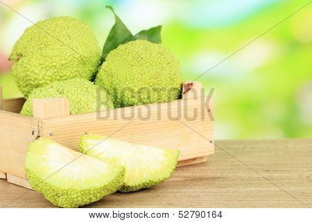 Osage Orange fruits (Maclura pomifera) in crate, on wooden table, on nature background