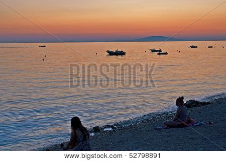 NOVALJA, ISLAND PAG, CROATIA - CIRCA SEPTEMBER 2010 - Two unknown girls relax in the early evening o