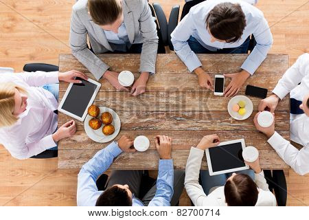 business, people, break and team work concept - close up of creative team meeting and drinking coffee with muffins during lunch in office
