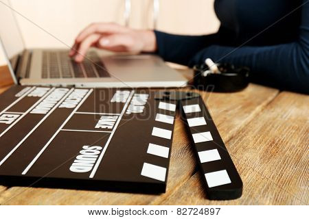 Female hands of scriptwriter working on laptop at desk on cupboard background