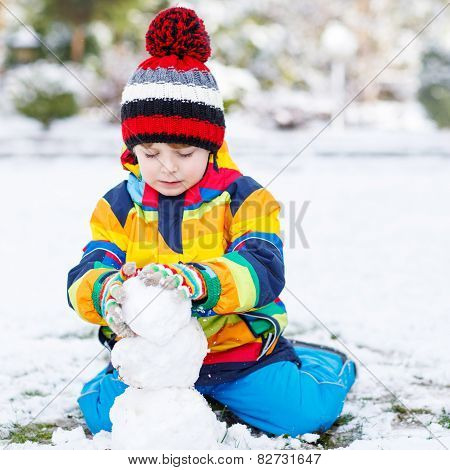 Lovely Little Boy In Colorful Clothes Making A Snowman