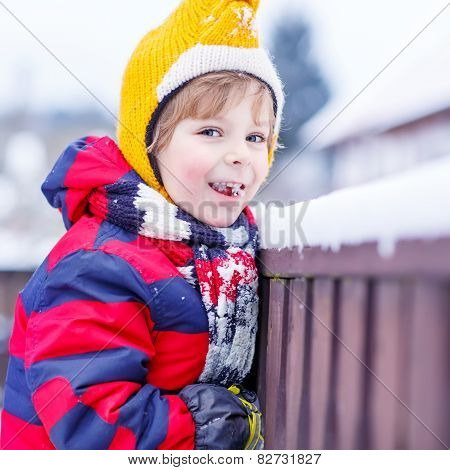 Little Kid Boy Eating And Tasting Snow, Outdoors On Cold Day