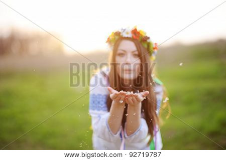 Girl In A Flower Wreath On His Head Blows Away The Fluff From His Hands