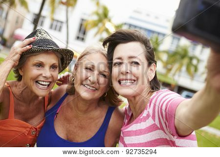 Three Senior Female Friends Taking Selfie In Park
