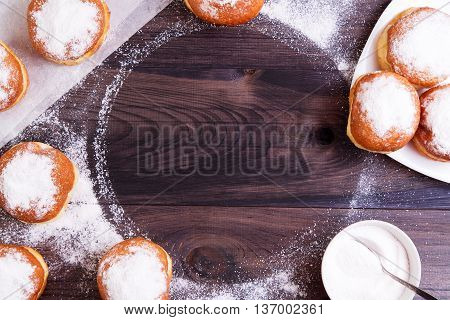 German donuts - berliner with jam and icing sugar on a wooden background. Berliner arranged as frame with copy space. Top view