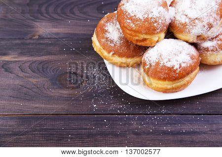 German donuts - berliner with icing sugar on plate on a dark wooden table