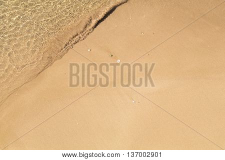 Beautiful crystal clear sea water, Gentle waves breaking on golden sand beach.  From above with copy space.