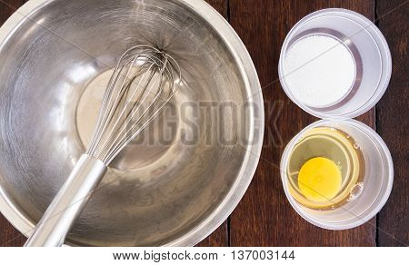 Ice cream making ingredients on plastic bowl and steel whisk.