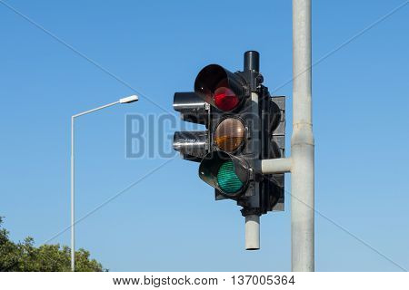 traffic light against a clear blue sky with lamp post in background