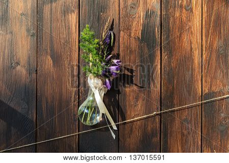 Beautiful blue flowers and green grass in the bottle, hanging on the background of a wooden wall.