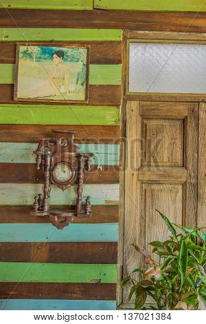 Antique clock is hang on the wooden wall on June 302016 in Thamuang Kanchanaburi Thailand.The old picture of thai queen also.