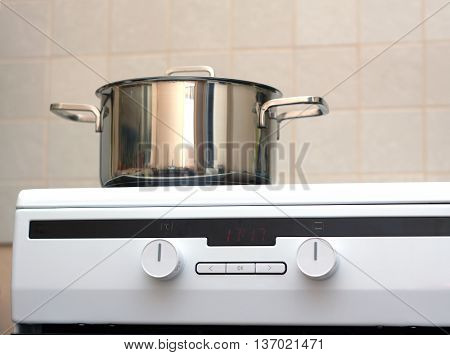 Metal steel saucepan with lid on modern kitchen electric stove. Photo closeup