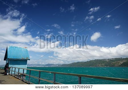 Fisherman on the old jetty at Petone to the Pacific ocean harbor against a background of blue sky, Wellington, New Zealand.