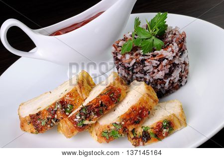 Slices of roasted chicken breast and a side dish of rice varied with ketchup