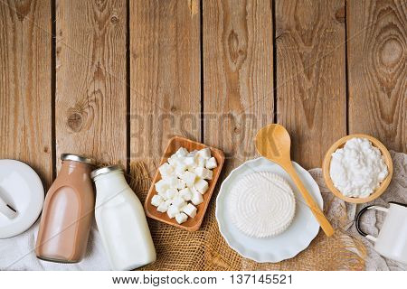 Milk bottles and cheese on wooden rustic background. View from above. Flat lay