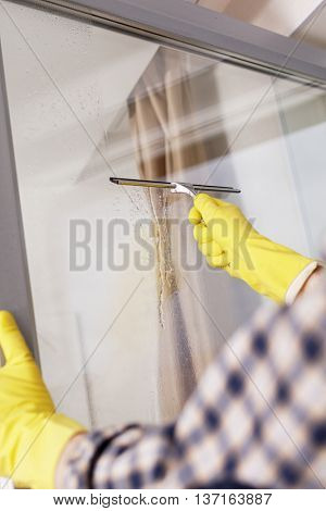 Mature man cleaning windows using squeegee