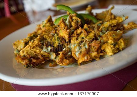 Deep fried breaded Indian onion pakora with green bell pepper garnish