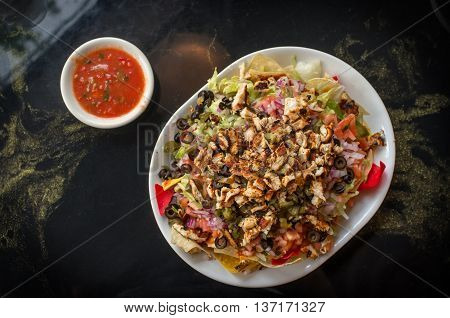 Colorful Mexican nachos with chicken black olives melted cheese jalapenos and more